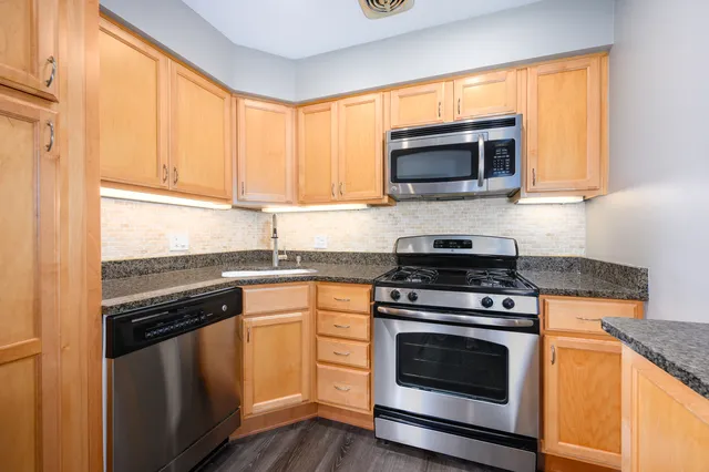 a kitchen with granite countertop a stove top oven microwave and cabinets
