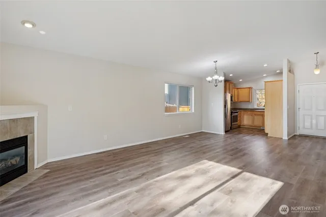 a view of an empty room with wooden floor and a kitchen