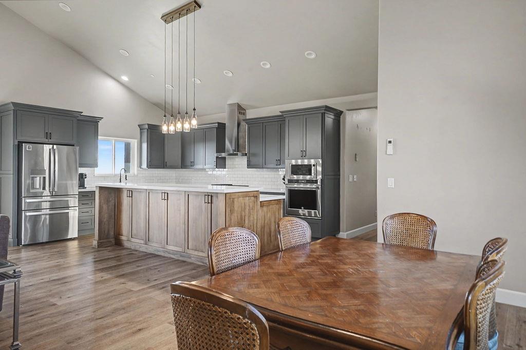 9515 Ham Luddy Road Mountain Ranch, CA 95246 - Photo 11 of 92 a large kitchen with stainless steel appliances granite countertop a stove refrigerator a oven a dining table and chairs with wooden floor
