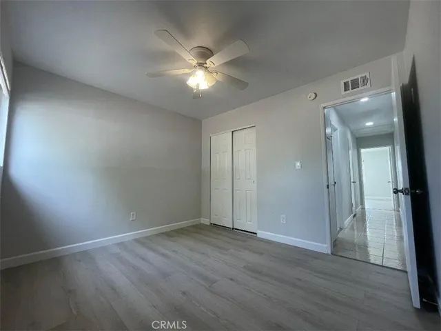 an empty room with wooden floor and fan