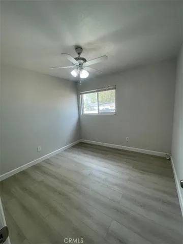 an empty room with wooden floor and fan