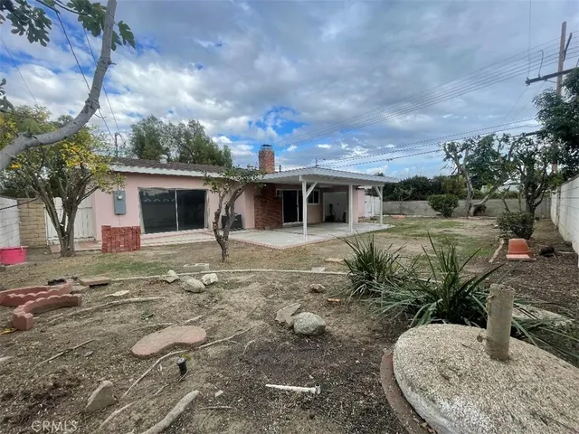 a view of a backyard with table and chairs potted plants and large tree
