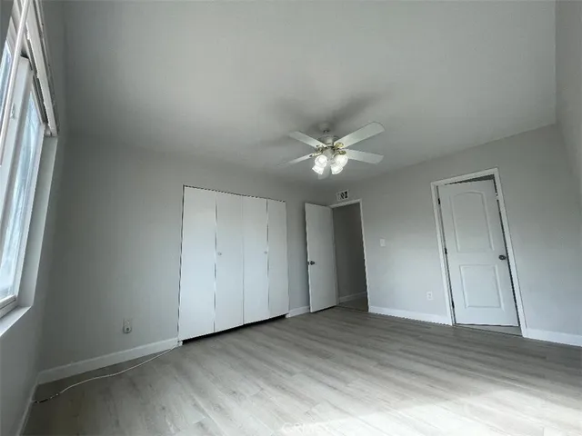 an empty room with wooden floor and fan