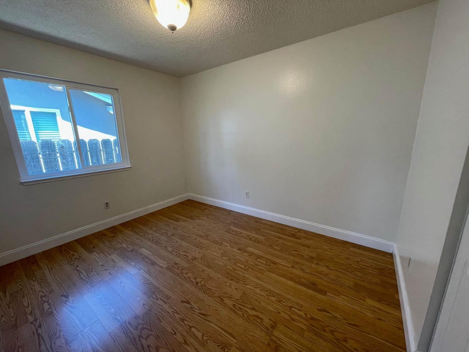 3101 Wyatt Way Modesto, CA 95350 - Photo 11 of 17 an empty room with wooden floor and windows