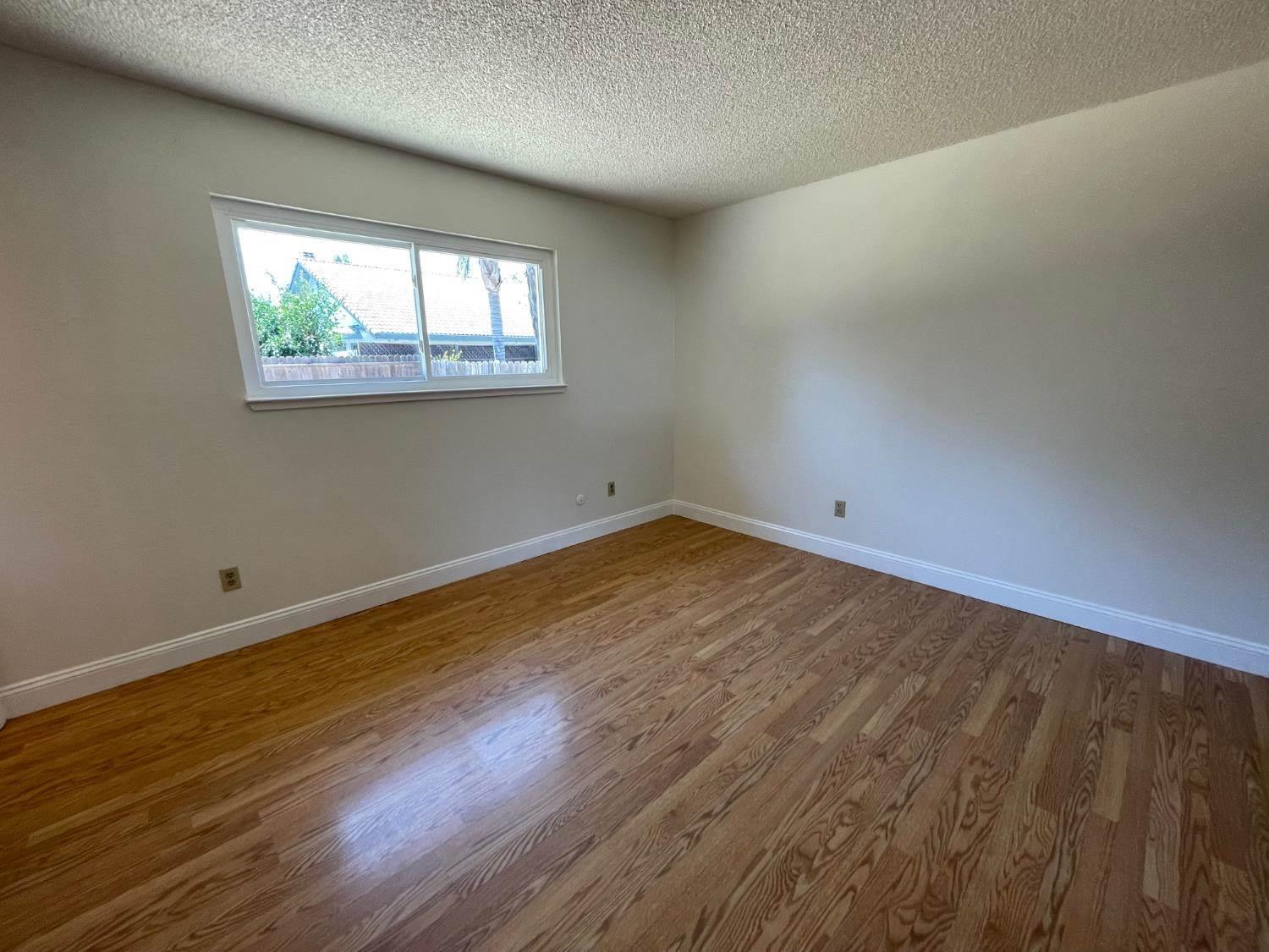 3101 Wyatt Way Modesto, CA 95350 - Photo 13 of 17 an empty room with wooden floor and windows