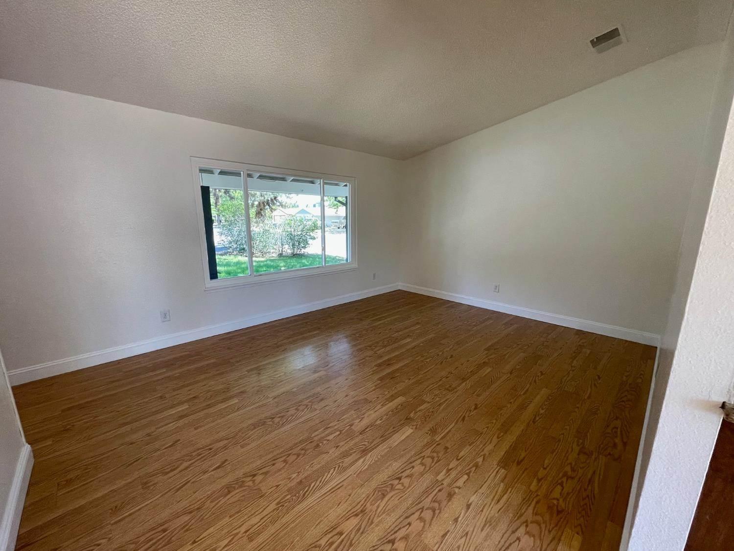 3101 Wyatt Way Modesto, CA 95350 - Photo 5 of 17 an empty room with wooden floor and windows