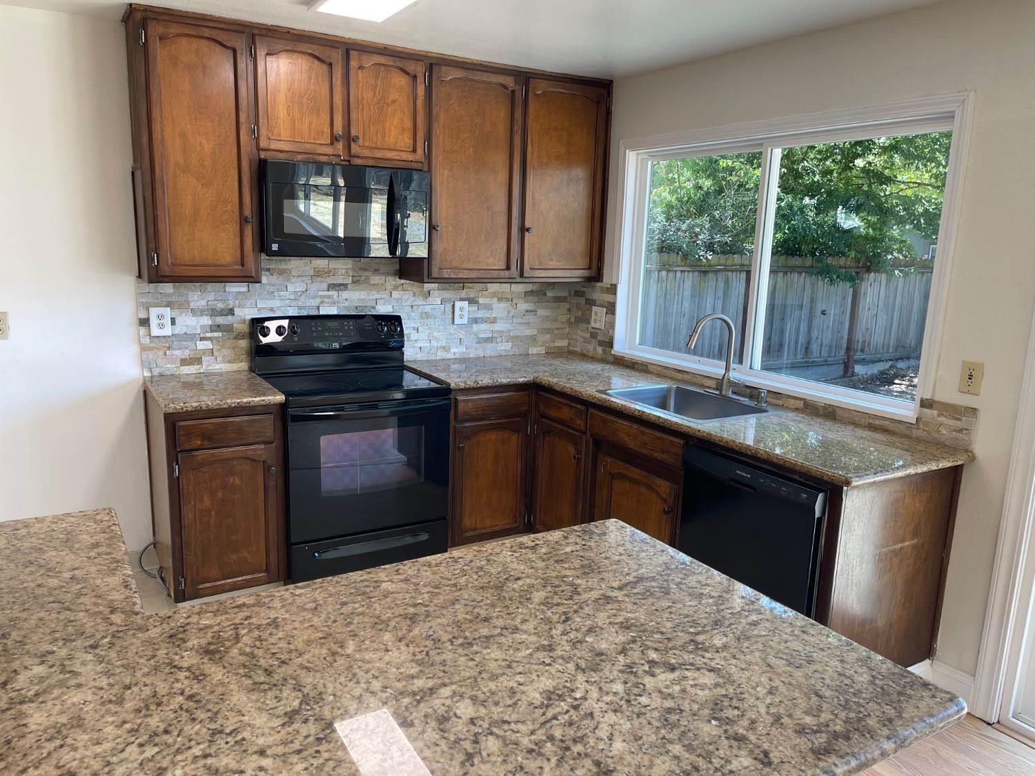 3101 Wyatt Way Modesto, CA 95350 - Photo 8 of 17 a kitchen with stainless steel appliances granite countertop a sink stove and microwave