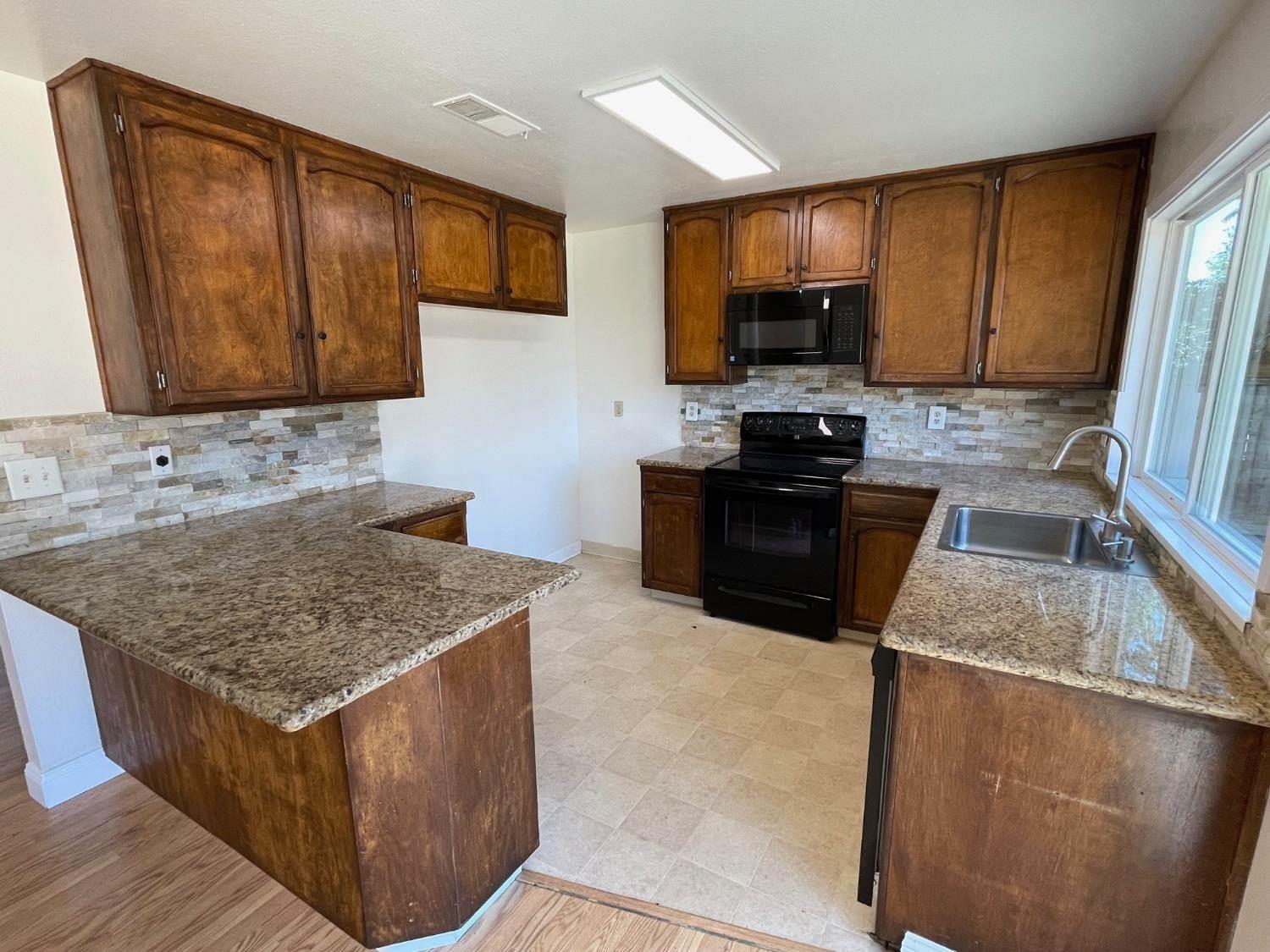 3101 Wyatt Way Modesto, CA 95350 - Photo 9 of 17 a kitchen with granite countertop a sink a stove top oven a refrigerator cabinets and wooden floor