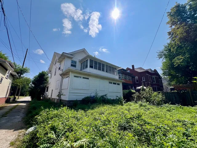 a view of a house with a big yard plants and large tree