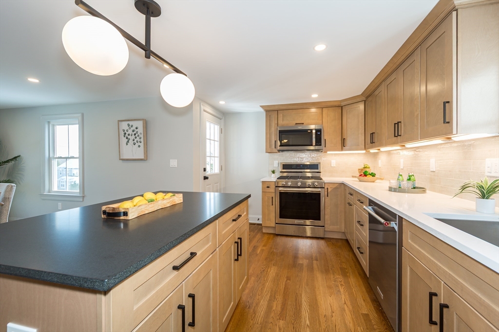 12 Bay State Road Natick, MA 01760 - Photo 11 of 35 a kitchen with stainless steel appliances granite countertop a refrigerator a stove and a sink with wooden floor