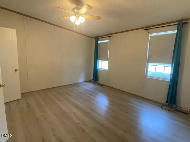 an empty room with wooden floor and windows