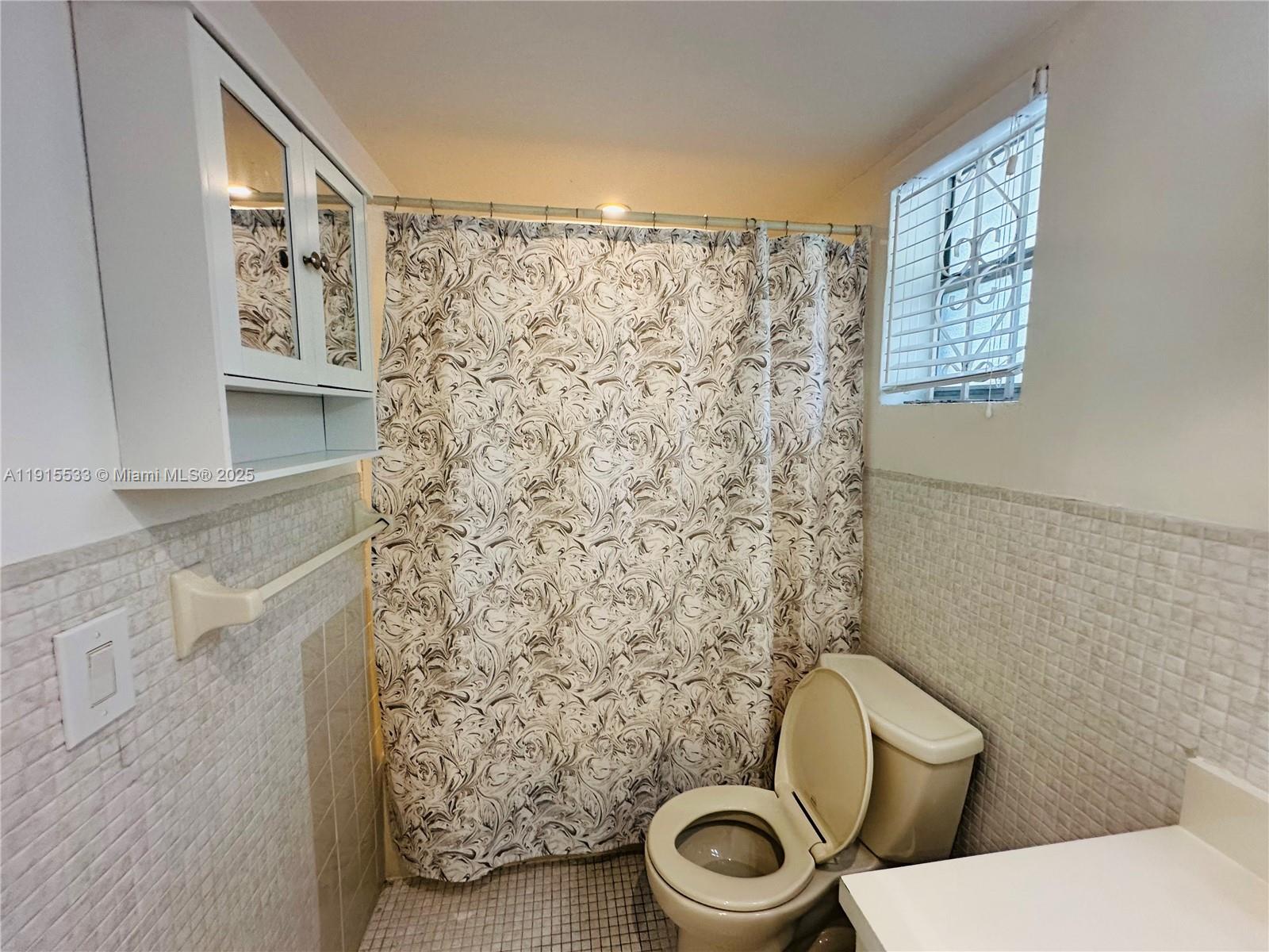 7505 Southwest 82nd Street, Unit 211 Miami, FL 33143 - Photo 9 of 17 a white toilet sitting next to a shower curtain
