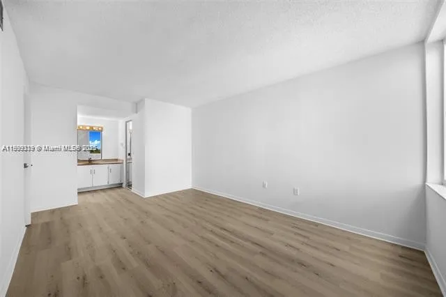 a view of kitchen and empty room with wooden floor