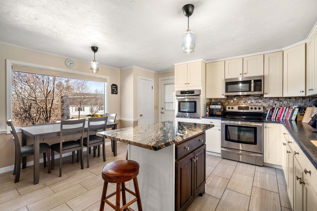 6 Wallace Road Sturbridge, MA 01566 - Photo 7 of 22 a kitchen with stainless steel appliances kitchen island granite countertop a stove top oven a sink a dining table and chairs