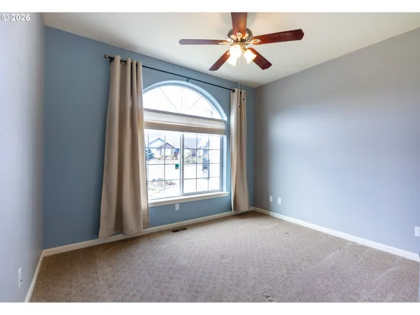 an empty room with windows and a ceiling fan