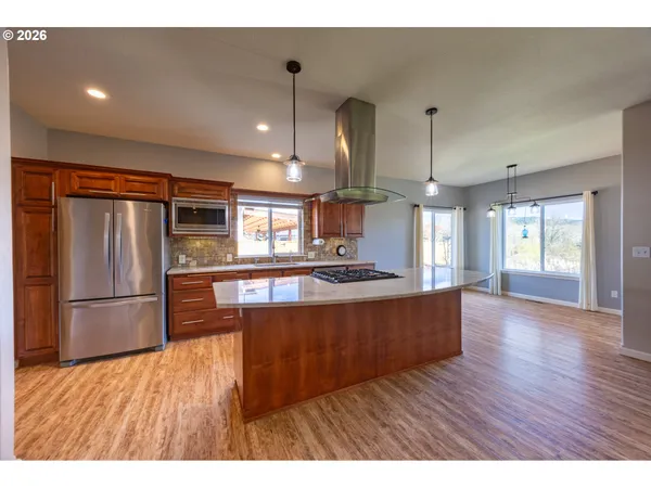 a large kitchen with stainless steel appliances wooden floors and large window