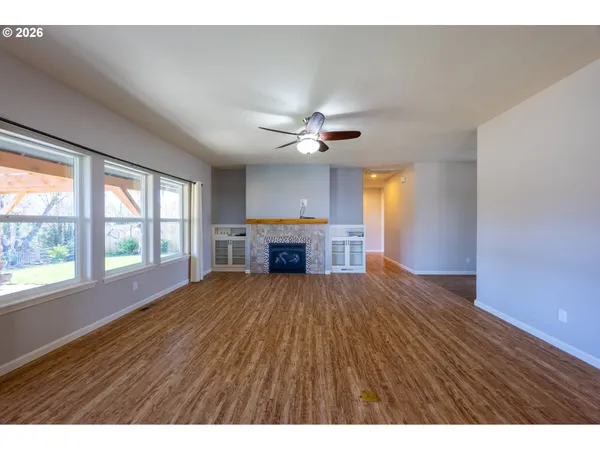 a view of an empty room with a window and a kitchen