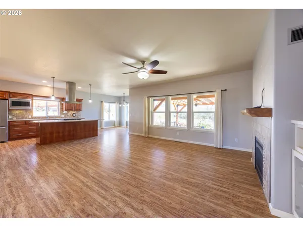 a view of a kitchen with a stove cabinets a ceiling fan and wooden floor