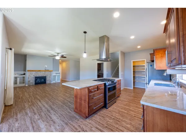 a kitchen with stainless steel appliances granite countertop a sink a stove and a wooden floors