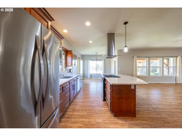 a open kitchen with stainless steel appliances granite countertop a refrigerator a stove and a wooden floors