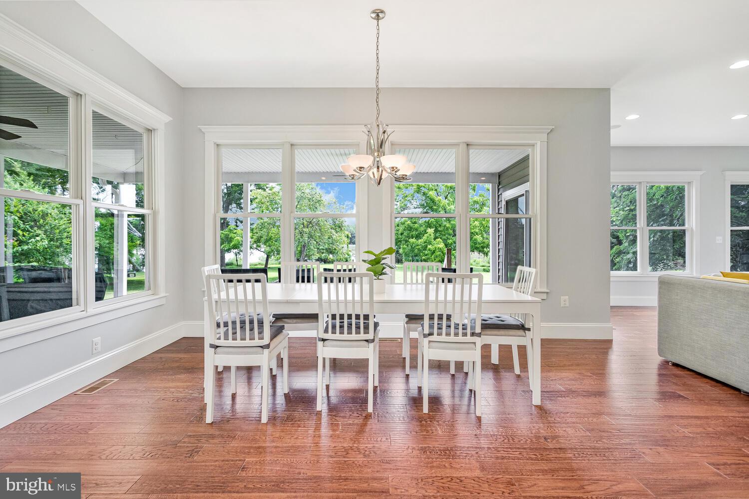 50333 Scotland Beach Road Scotland, MD 20687 - Photo 12 of 80 a dining room with wooden floor a chandelier a glass table and chairs