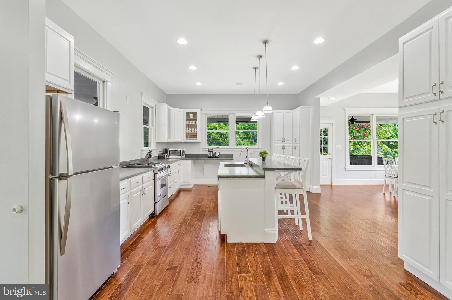 50333 Scotland Beach Road Scotland, MD 20687 - Photo 19 of 80 a kitchen with kitchen island wooden floors white appliances and windows