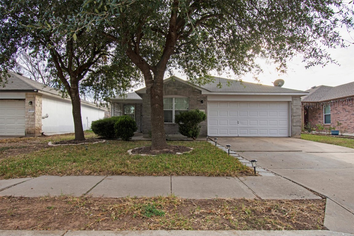 Single story home with driveway, a garage, and brick siding