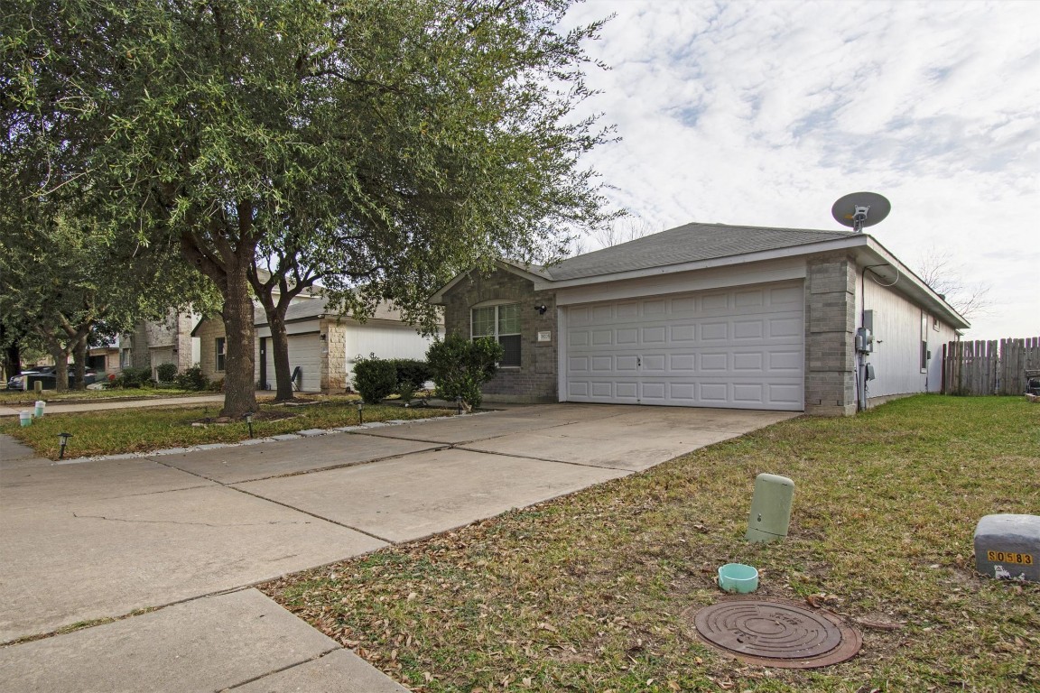 18205 Topsail Street Manor, TX 78653 - Photo 3 of 29 Ranch-style home featuring concrete driveway, an attached garage, brick siding, and a front yard