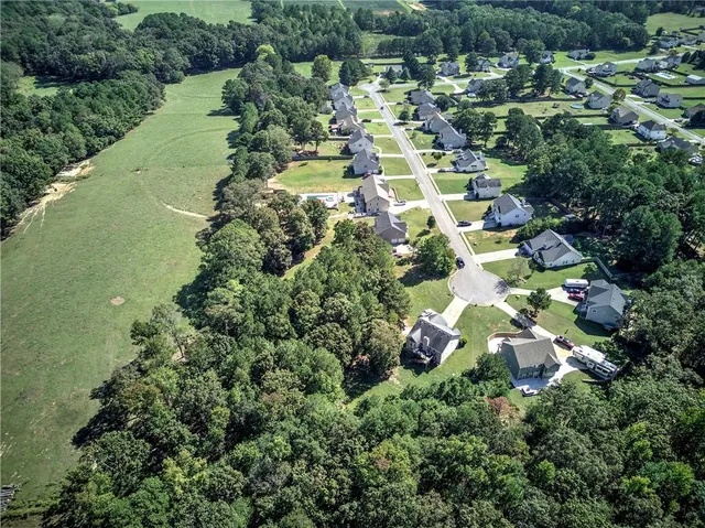 an aerial view of residential houses with outdoor space and trees all around