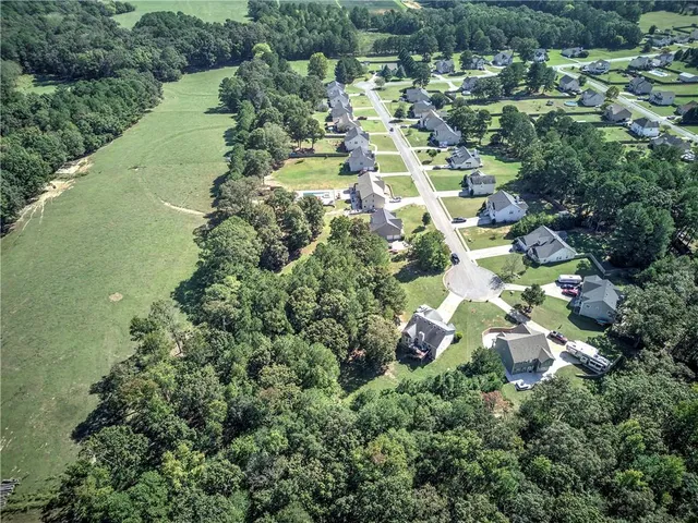 an aerial view of residential houses with outdoor space and trees all around