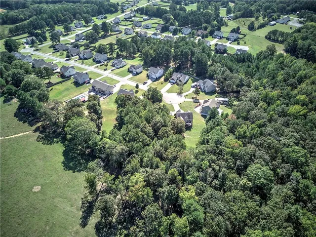 an aerial view of residential houses with outdoor space and trees all around