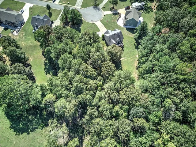 an aerial view of residential house with outdoor space and trees all around