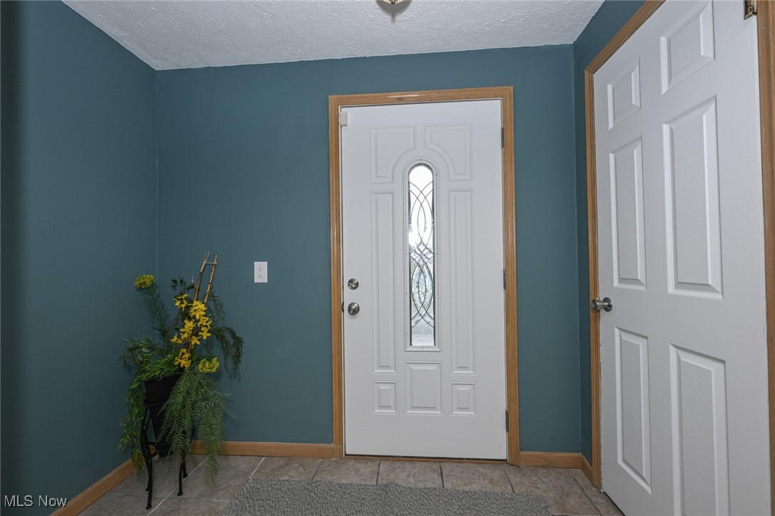1164 Copley Road Akron, OH 44320 - Photo 4 of 50 Entrance foyer with a textured ceiling, light tile patterned floors, and baseboards
