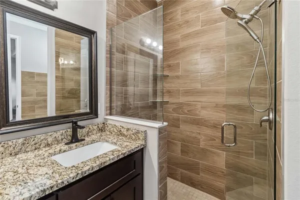 a bathroom with a granite countertop sink a mirror and shower
