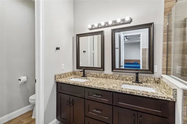 a bathroom with a granite countertop sink a toilet and a mirror