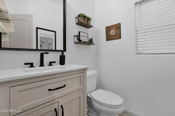 a bathroom with a toilet sink vanity and mirror