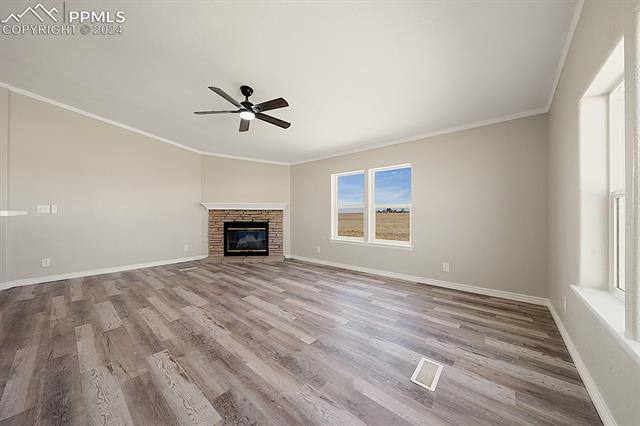 8160 Edison Road Yoder, CO 80864 - Photo 13 of 42 Unfurnished living room with ornamental molding, a fireplace, ceiling fan, and light hardwood / wood-style flooring