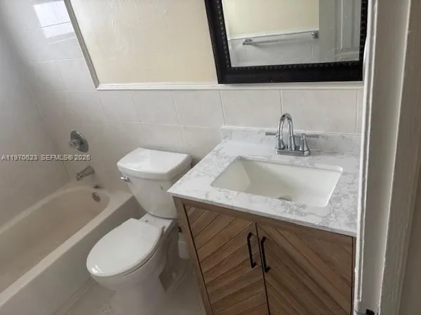 a bathroom with a granite countertop toilet sink and mirror
