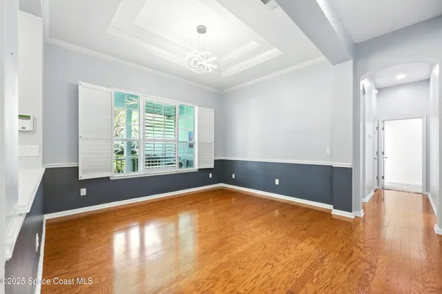 a view of an empty room with window and wooden floor
