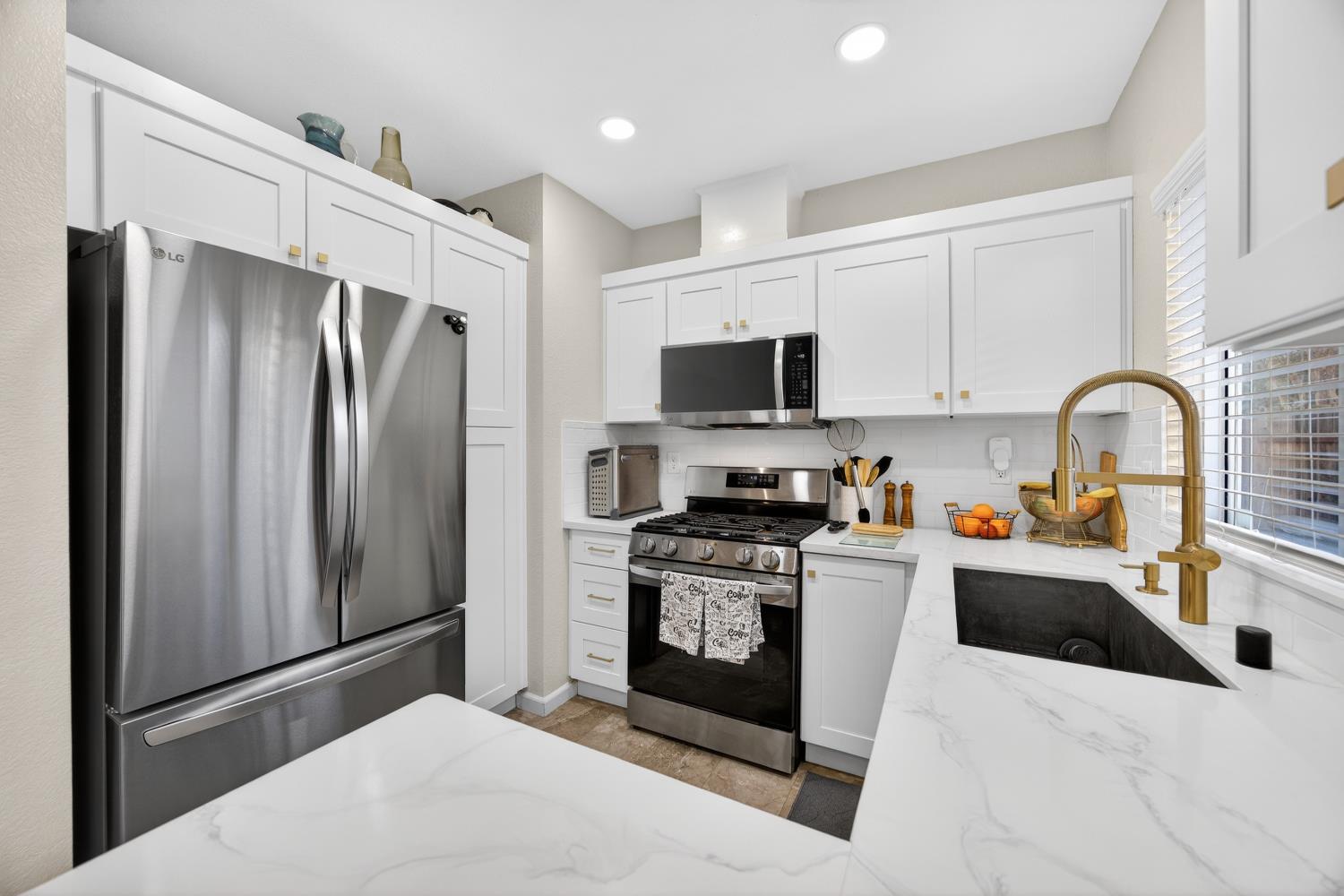 9365 Laguna Pointe Way Elk Grove, CA 95758 - Photo 13 of 24 a kitchen with stainless steel appliances a refrigerator sink and a stove top oven