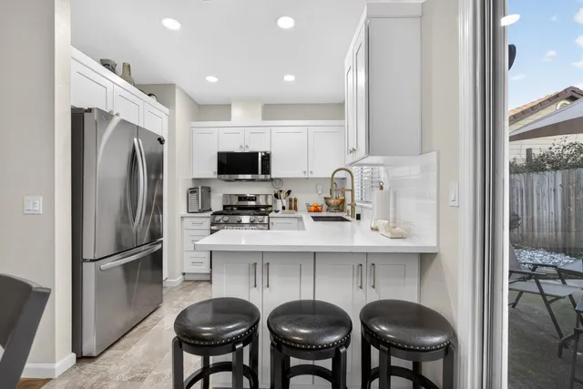 a kitchen with stainless steel appliances granite countertop a dining table and chairs