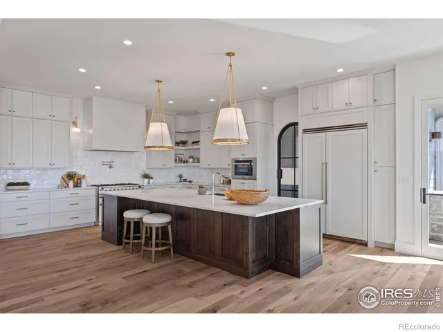 a kitchen with kitchen island a sink a stove a refrigerator and white cabinets