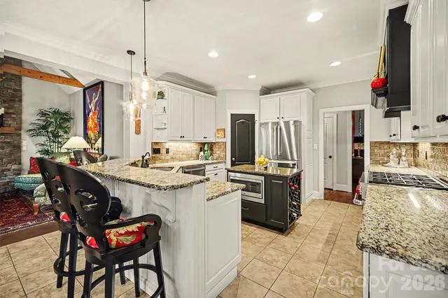 a kitchen with stainless steel appliances granite countertop a stove refrigerator a sink dishwasher a dining table and chairs with wooden floor