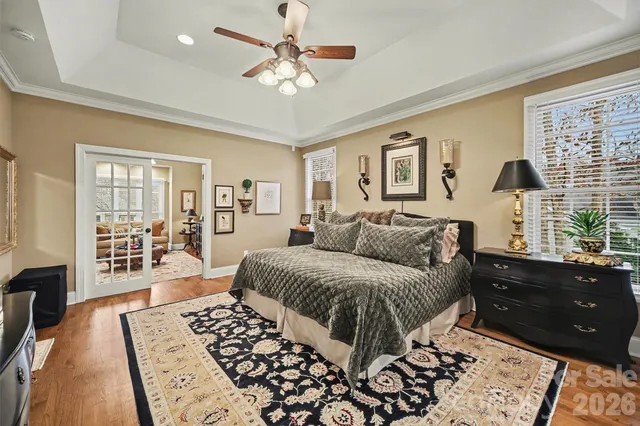 a spacious bedroom with a bed a dresser and wooden floor