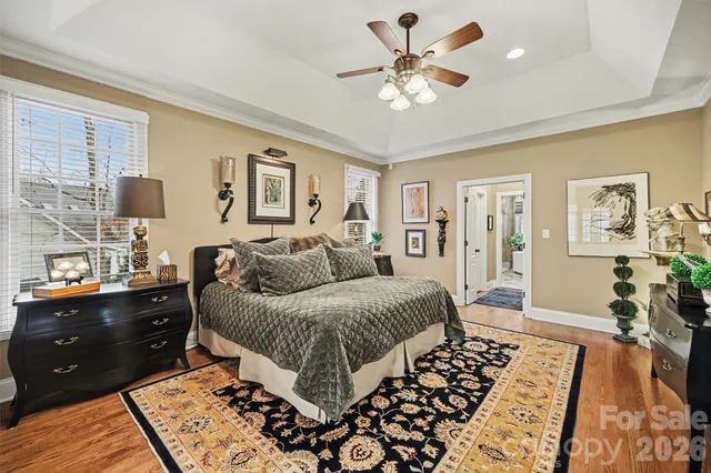 a spacious bedroom with a bed a dresser and wooden floor