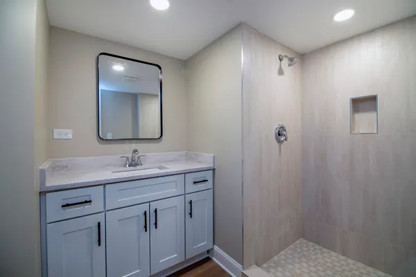 a en suite bathroom with a granite countertop sink and mirror