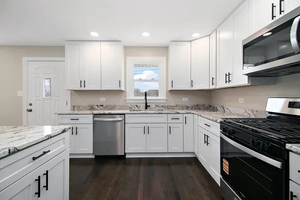 a kitchen with granite countertop white cabinets stainless steel appliances and a sink