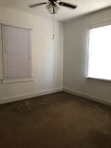 an empty room with a window and a ceiling fan