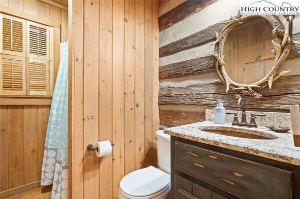 a bathroom with a granite countertop sink vanity mirror and toilet