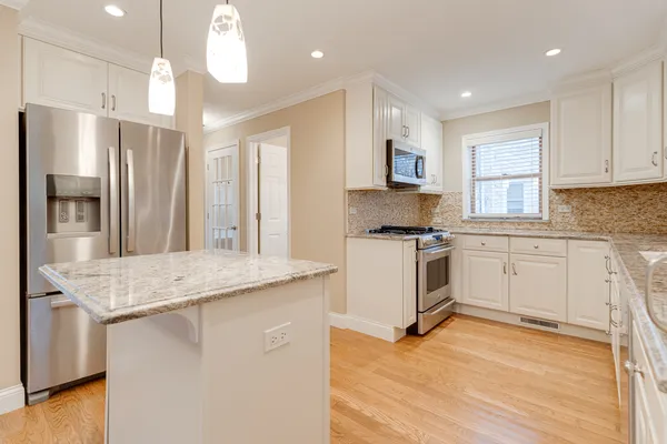 a kitchen that has a lot of white cabinets and stainless steel appliances